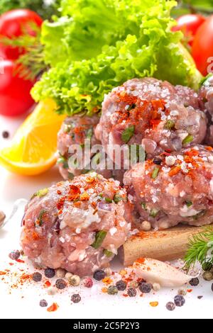 Frische Fleischbällchen mit verschiedenen Gemüsesorten. Hausgemachte Fleischbällchen isoliert auf weiß mit verschiedenen Gemüse und Gewürzen. Stockfoto