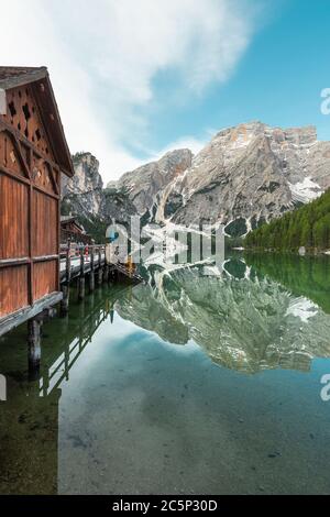 Blick auf ikonisches Bootshaus und Boote mit dem Seekofel, der sich im klaren, ruhigen Wasser des Pragser Wildsee (Pragser Pragser See) in den Dolomiten spiegelt, Stockfoto