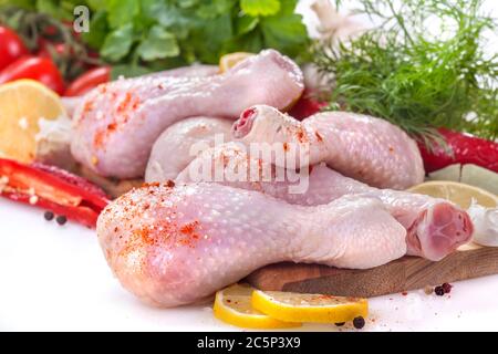 Frische Hähnchenschenkel mit Tomaten, Zitrone und Gewürzen auf weißem Hintergrund Stockfoto