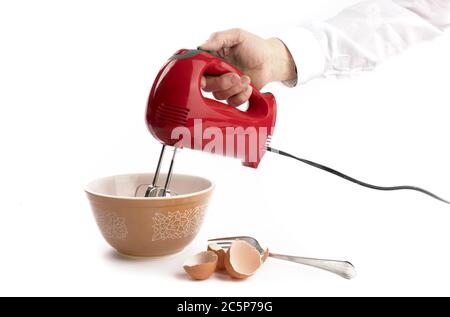 Ein Koch mit einem roten elektrischen Mixer mit braunen Eierschalen Isoliert auf Weiß Stockfoto