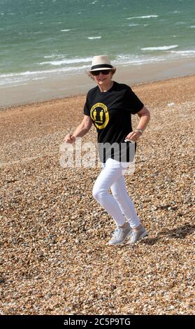 Southsea, Portsmouth, England, Großbritannien. 2020. Ältere Frau am Strand laufen tragen, halten Sie Ihre Distanz T-Shirt während der Covid-19 Epidemie. Stockfoto