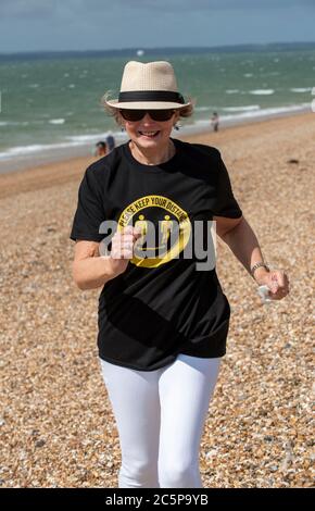 Southsea, Portsmouth, England, Großbritannien. 2020. Ältere Frau am Strand laufen tragen, halten Sie Ihre Distanz T-Shirt während der Covid-19 Epidemie. Stockfoto