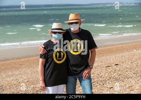 Southsea, Portsmouth, England, Großbritannien. 2020. Ältere Paar am Strand mit Masken und halten Sie Ihre Distanz T-Shirts während der Covid-19 Epidemie. Stockfoto