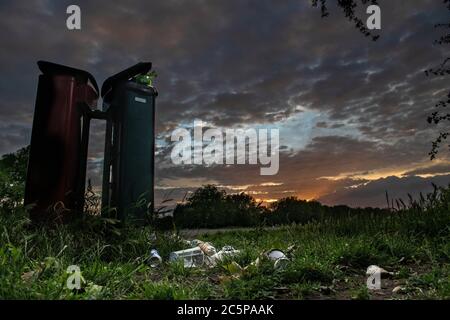 Überlaufenen Mülltonnen in einem Londoner Park am Ende des Tages unter einem dramatischen Sonnenuntergang Stockfoto