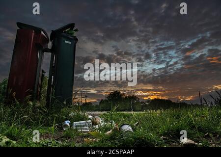 Überlaufenen Mülltonnen in einem Londoner Park am Ende des Tages unter einem dramatischen Sonnenuntergang Stockfoto