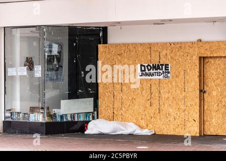 Obdachlose Person rauh schlafen in Tür des geschlossenen Shop in High Street, Southend on Sea, Essex, Großbritannien. Rauer Schlaf auf dem Boden. Spenden Sie unerwünschte Gegenstände Stockfoto