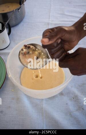 Baobab Fruit sweet traditioneller hausgemachter Milch Joghurt, der aus einer Pfanne in eine Schüssel gespannt wird Stockfoto