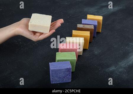 Natürliche SPA Seife aus Ziegenmilch. Handgemachte, Bio-Seife, Körperpflege. Viele verschiedene handgemachte Seifenstücke auf schwarzem Holz Hintergrund. Stockfoto