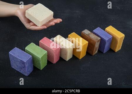 Natürliche SPA Seife aus Ziegenmilch. Handgemachte, Bio-Seife, Körperpflege. Viele verschiedene handgemachte Seifenstücke auf schwarzem Holz Hintergrund. Stockfoto