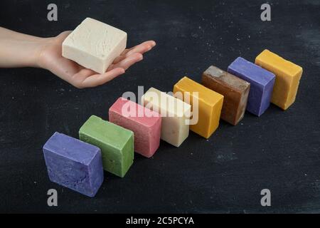 Natürliche SPA Seife aus Ziegenmilch. Handgemachte, Bio-Seife, Körperpflege. Viele verschiedene handgemachte Seifenstücke auf schwarzem Holz Hintergrund. Stockfoto