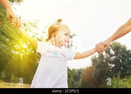 Nettes kleines Mädchen nehmen Hände mit ihren Verwandten Menschen. Walking with Kids Konzept Bild. Stockfoto