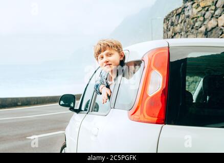 Blonde Haare Teenager junge Blick aus der hinteren Passanten Tür der Economy-Klasse Auto und lächelnd.Mietwagen und Reisen durch Auto Konzept Bild. Stockfoto