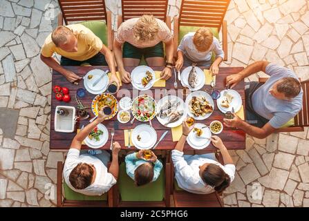 Großes Familienessen mit mehreren Generationen im Prozess. Bild von oben auf dem Tisch mit Essen und Händen. Lebensmittelkonsum und generationsübergreifendes Familienkonzept ima Stockfoto