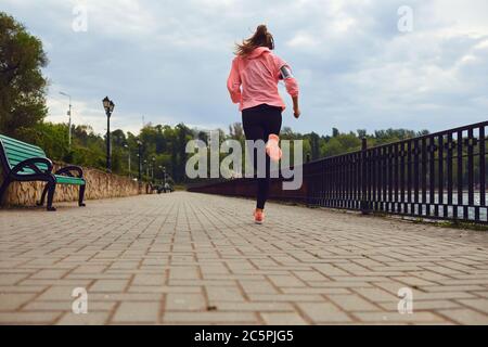 Rückansicht einer Frau in Sportkleidung, die am Flussufer entlang läuft, Raum kopieren. Jogger beim Training, Vorbereitung auf den Marathon Stockfoto
