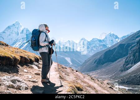 Junge Wandererin Backpacker-Frau, die während der Route des Everest Base Camps in der Nähe von Dingboche, Nepal, mit Wanderstöcken unterwegs ist. AMA Dablam 6812 m. Stockfoto