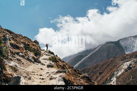 Junge Wandererin Backpacker-Frau, die beim Wandern in Höhenlagen die Bremse zieht Everest Base Camp (EBC) Route mit schneebedeckten Himalaya-Gipfeln im Hintergrund. Stockfoto