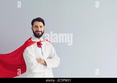 Superhelden Arzt in rotem Umhang auf grauem Hintergrund. Medic in Superman Kostüm bereit, Virus oder Infektion zu bekämpfen Stockfoto