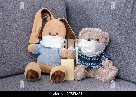 Coronovirus Ausbruch in der Welt. Tragen Sie medizinische Masken und waschen Sie Ihre Hände öfter. Weiches Spielzeug Hase und Bär in medizinischen Masken und Seife in Pfoten zu schützen Stockfoto