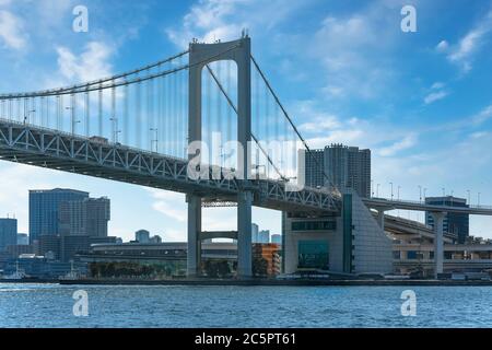 tokio, japan - april 04 2020: Nahaufnahme auf der zweischichtigen Schnellstraße der hängeenden Rainbow Bridge in der Tokyo Bay mit den Wolkenkratzern von Shin Stockfoto