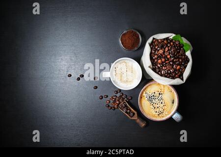 Stillleben mit Kaffee. Kaffeetassen und Kaffeebohnen in Leinwandtasche auf schwarzem Küchentisch Hintergrund. Flach liegend. Stockfoto