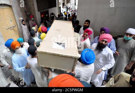 Mitglieder der Sikh-Gemeinde tragen den Sarg ihrer Verwandten, die bei einem Unfall zwischen einem Bus und einem Zug in der Nähe von Sheikhupura am Freitagnachmittag während einer Trauerfeier in Gurdwara Bhai Joga Singh in Peshawar am Samstag, 4. Juli 2020 getötet wurden. Zwanzig Menschen, meist Sikh-Pilger, werden bei einem Unfall zwischen Bus und Zug in der Nähe von Sheikhupura am Freitagnachmittag tot gefürchtet. Der Bus, der die Pilger trug, wurde an einer unbemannten Eisenbahnkreuzung durch den Karachi-gebundenen Schah Hussain Express getroffen. Stockfoto