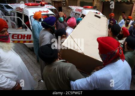 Mitglieder der Sikh-Gemeinde tragen den Sarg ihrer Verwandten, die bei einem Unfall zwischen einem Bus und einem Zug in der Nähe von Sheikhupura am Freitagnachmittag während einer Trauerfeier in Gurdwara Bhai Joga Singh in Peshawar am Samstag, 4. Juli 2020 getötet wurden. Zwanzig Menschen, meist Sikh-Pilger, werden bei einem Unfall zwischen Bus und Zug in der Nähe von Sheikhupura am Freitagnachmittag tot gefürchtet. Der Bus, der die Pilger trug, wurde an einer unbemannten Eisenbahnkreuzung durch den Karachi-gebundenen Schah Hussain Express getroffen. Stockfoto