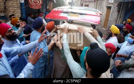 Mitglieder der Sikh-Gemeinde tragen den Sarg ihrer Verwandten, die bei einem Unfall zwischen einem Bus und einem Zug in der Nähe von Sheikhupura am Freitagnachmittag während einer Trauerfeier in Gurdwara Bhai Joga Singh in Peshawar am Samstag, 4. Juli 2020 getötet wurden. Zwanzig Menschen, meist Sikh-Pilger, werden bei einem Unfall zwischen Bus und Zug in der Nähe von Sheikhupura am Freitagnachmittag tot gefürchtet. Der Bus, der die Pilger trug, wurde an einer unbemannten Eisenbahnkreuzung durch den Karachi-gebundenen Schah Hussain Express getroffen. Stockfoto