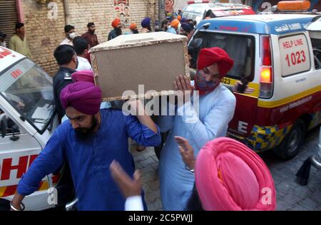 Mitglieder der Sikh-Gemeinde tragen den Sarg ihrer Verwandten, die bei einem Unfall zwischen einem Bus und einem Zug in der Nähe von Sheikhupura am Freitagnachmittag während einer Trauerfeier in Gurdwara Bhai Joga Singh in Peshawar am Samstag, 4. Juli 2020 getötet wurden. Zwanzig Menschen, meist Sikh-Pilger, werden bei einem Unfall zwischen Bus und Zug in der Nähe von Sheikhupura am Freitagnachmittag tot gefürchtet. Der Bus, der die Pilger trug, wurde an einer unbemannten Eisenbahnkreuzung durch den Karachi-gebundenen Schah Hussain Express getroffen. Stockfoto