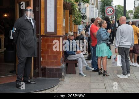 London 4. Juli 2020 Super Saturday UK. Portier und Kellner tragen eine Gesichtsmaske. Bars und Pubs sind mit Einschränkungen geöffnet, in der Bar gibt es nur eine begrenzte Anzahl von Trinkern. Portobello Road junge Londoner. 2020er Jahre England HOMER SYKES Stockfoto