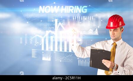 Gut aussehender Geschäftsmann mit Helm Zeichnung JETZT EINSTELLUNG Inschrift, Architektur Konzept Wipl Stockfoto