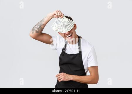 Kleinhandelsunternehmen, Zahlungsverkehr und Mitarbeiter Konzept. Netter und verspielter Cafe-Besitzer, Kellner mit riesigen Trinkgeldern, tanzend mit Geld und lachend Stockfoto