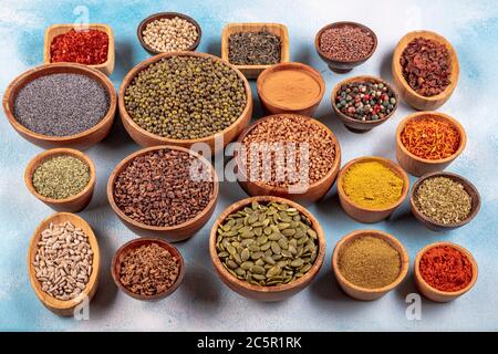 Eine Auswahl an verschiedenen bunten Gewürzen auf einem Holztisch in Schüsseln. Verschiedene Arten von Gewürzen auf Holzhintergrund. Stockfoto