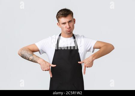 Inhaber kleiner Unternehmen, Café und Konzept des Personals. Düster und skeptisch Barista in schwarzer Schürze Pouting, wird immer traurig, wenn der Kunde nicht klicken Stockfoto