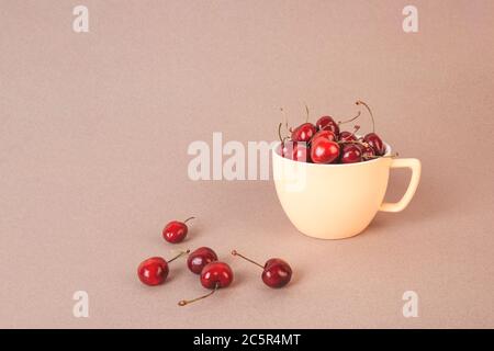 Kirsche in einer gelben Tasse auf beigem Hintergrund. Stockfoto