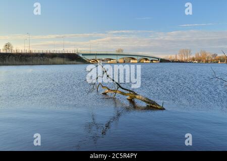 Brücke über einen breiten Fluss und Lagune bei Sonnenaufgang, malerische Wolken am Himmel. Feder. Stockfoto