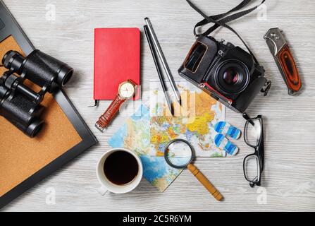 Unverzichtbares Reiseaccessoires auf hellem Holzhintergrund. Urlaubsartikel. Outfit des Reisenden. Draufsicht. Flach liegend. Stockfoto