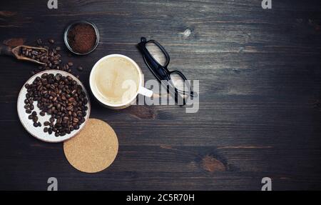 Stillleben mit Kaffeetasse, Kaffeebohnen, gemahlenem Pulver, Bieruntersetzer und Gläsern auf Vintage-Holzhintergrund. Viel Platz für den Text. Obere V Stockfoto