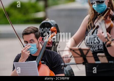 Columbus, Ohio, USA. Juli 2020. Ein Musiker passt seine Maske während einer Black Lives Matter Protest, und Violine Mahnwache zu Ehren von Elijah McClain, Samstag, 4. Juli im Rathaus in Columbus, Ohio. Quelle: Andrew Dolph/ZUMA Wire/Alamy Live News Stockfoto