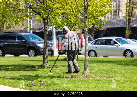 Mann, der einen Metalldetektor in einem Park benutzt, um nach unterirdischen Gegenständen zu suchen. Stockfoto