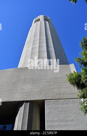 Blick nach oben von der Basis des Coit Tower in Richtung der Spitze an einem klaren Tag mit blauem Himmel und Bäumen. Telegraph Hill, San Francisco, Kalifornien Stockfoto