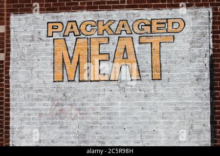 Die Wörter verpacktes Fleisch stenciled auf einer Ziegelwand mit dunkelroten Ziegel und weiß bemalten Ziegel. Stockfoto
