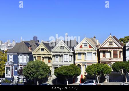 Die Painted Ladies aus dem Alamo Square Park. Die Skyline von San Francisco und die Transamerica Pyramide sind hinter den viktorianischen Häusern zu sehen. Stockfoto