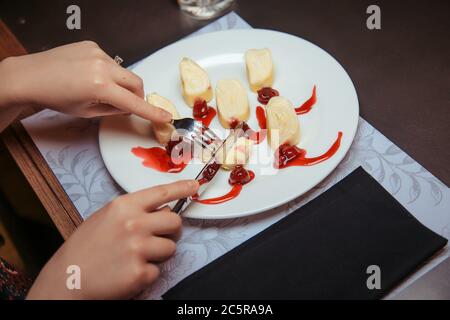 Eine Frau schneidet Dessert mit Pfannkuchen und Kirschen von Hand Stockfoto