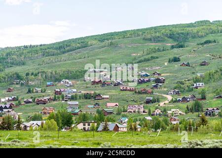 Mount Crested Butte Dorf Stadthäuser im Sommer mit vielen hölzernen Unterkünften Gebäude auf Hügel mit grünen üppigen Farben Gras Stockfoto