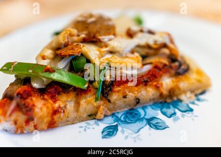 Hausgemachte glutenfreie Pizza Scheibe mit Tomatensauce, Belag von grünen Paprika Pilze und vegane Wurst und geschmolzenem Cashew-Käse auf blau gekocht Stockfoto