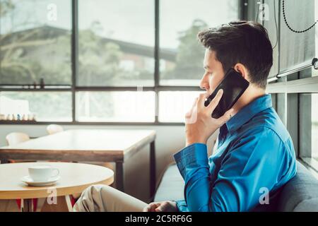 Businessman Consulting Partner per Telefon während der Sitzung im Café. Stockfoto