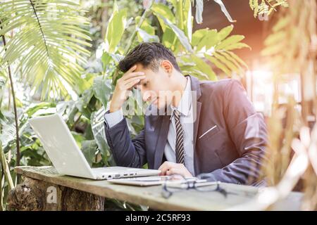 Geschäftsmann mit Kopfschmerzen bei der Arbeit mit Laptop. Stockfoto
