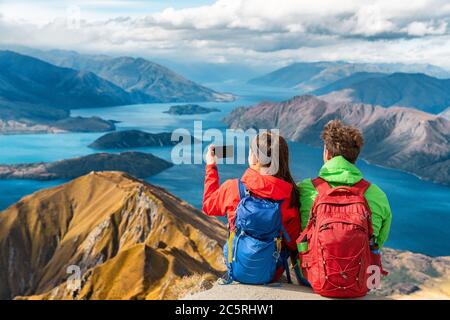 Wanderer, die auf dem Berggipfel auf Wanderreise Urlaub Blick - Paar fotografieren mit dem Telefon. Fernweh Abenteuer Menschen entspannen. Gipfel Stockfoto