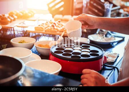 Der Koch bereitet das Dessert auf den Tisch zu und gießt Kokosmilch. Stockfoto
