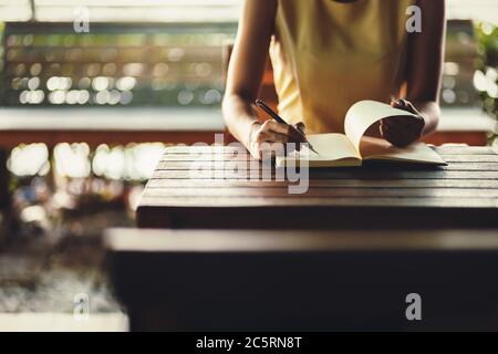 Hand halten Stift und schreiben ein Buch auf den Tisch. Stockfoto